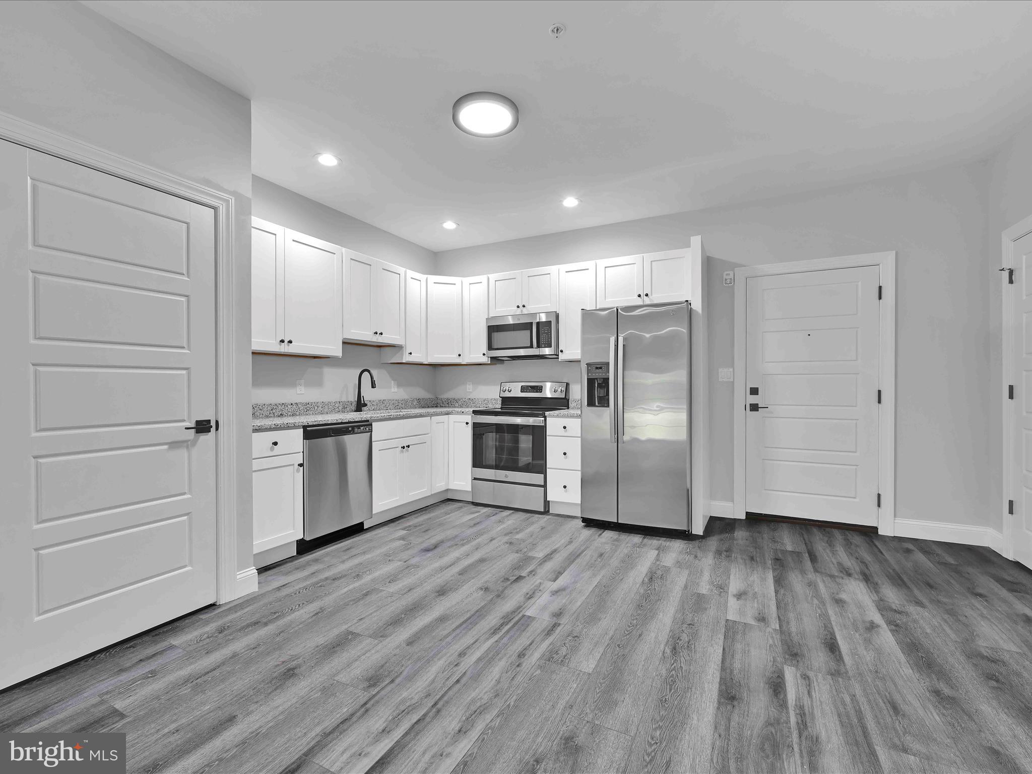 500-800 Paramount Boulevard, Unit 101312 Orwigsburg, PA 17961 - Photo 23 of 66 a kitchen with wooden floors stainless steel appliances and white cabinets
