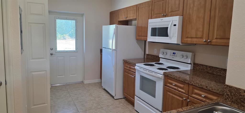 26172 Explorer Road, Unit 4 Punta Gorda, FL 33983 - Photo 4 of 11 a kitchen with stainless steel appliances granite countertop white cabinets a refrigerator a stove and a sink