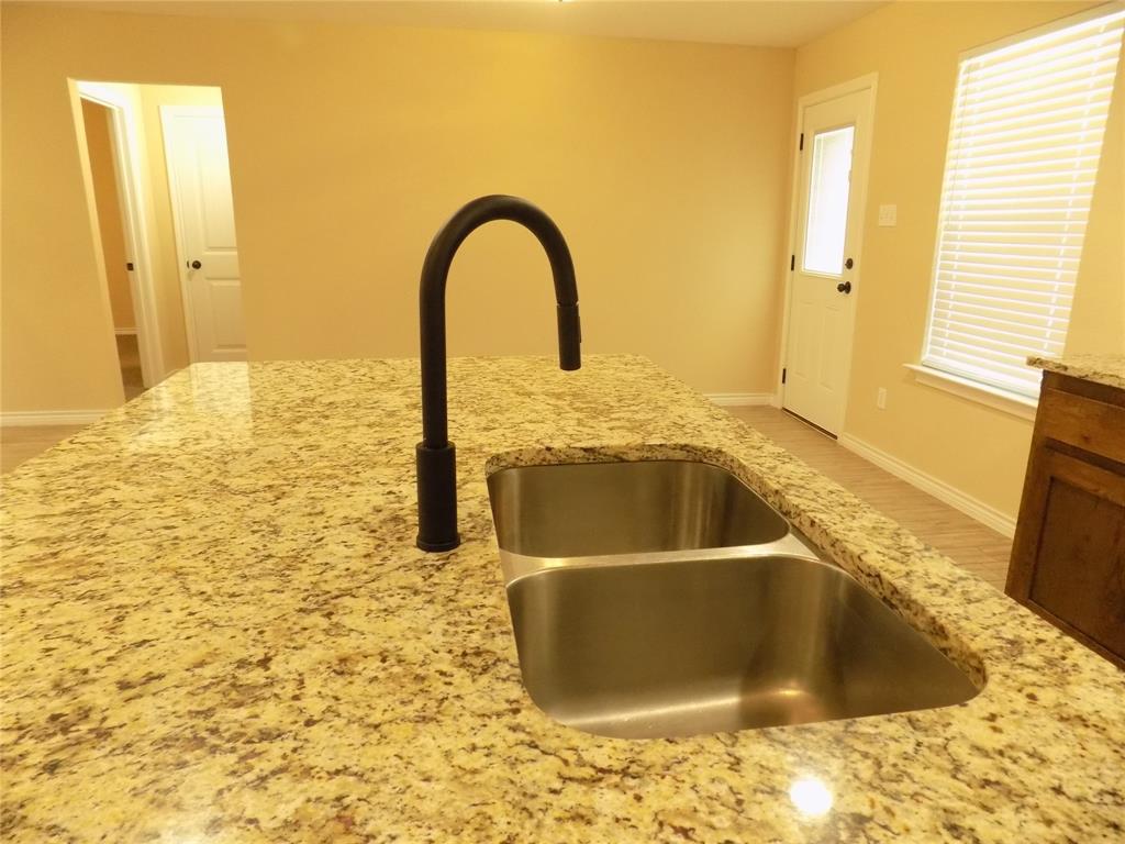 506 Pecan Tree Court Poolville, TX 76487 - Photo 17 of 36 Closer view of under cabinet stainless steel sink and granite counter top; eat in kitchen island