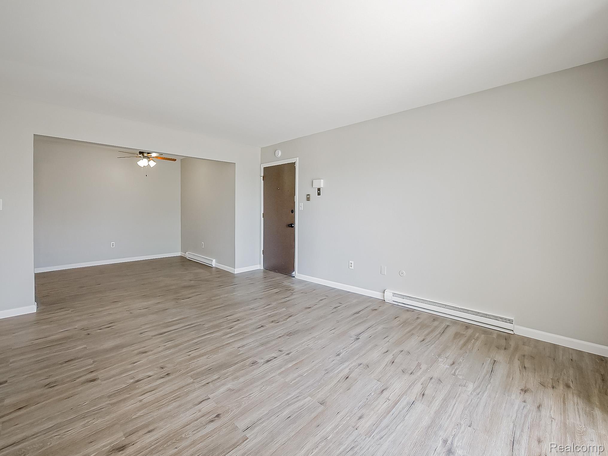 125 East Van Riper Road, Unit 5 Fowlerville, MI 48836 - Photo 6 of 23 Spare room featuring a baseboard radiator, ceiling fan, and light wood finished floors