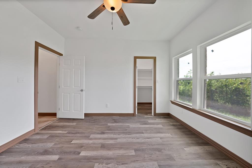 206 Hix Road Cleburne, TX 76031 - Photo 18 of 40 Unfurnished bedroom featuring a spacious closet, light wood-type flooring, and ceiling fan