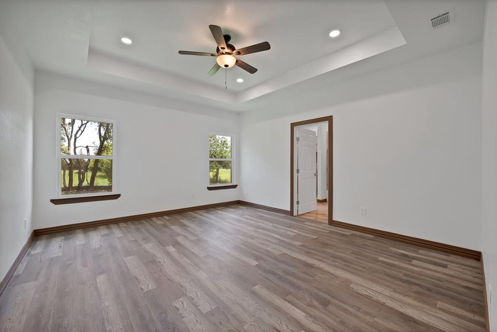206 Hix Road Cleburne, TX 76031 - Photo 32 of 40 Empty room featuring a raised ceiling, light wood-style flooring, ceiling fan, and recessed lighting