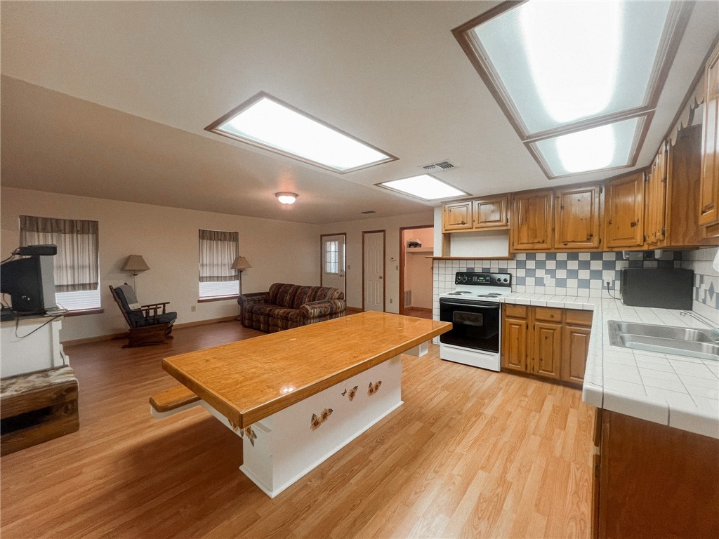 156 Naylor Road Calliham, TX 78007 - Photo 23 of 28 a large living room with stainless steel appliances kitchen island granite countertop a large kitchen island a stove a sink dishwasher and white cabinets with wooden floor