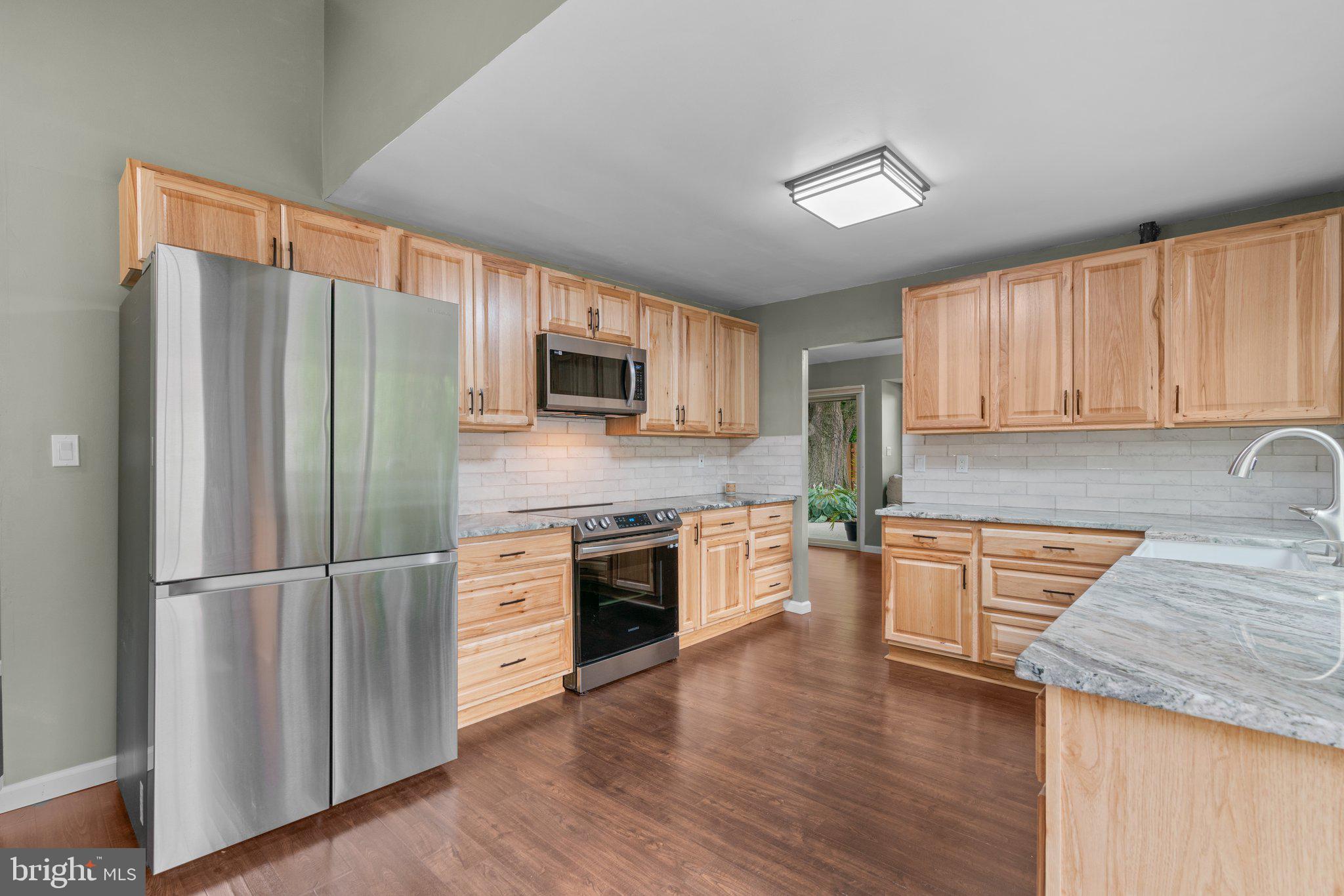 5367 Flight Feather Columbia, MD 21045 - Photo 3 of 42 a kitchen with stainless steel appliances granite countertop a refrigerator a stove top oven a sink and dishwasher with wooden floor