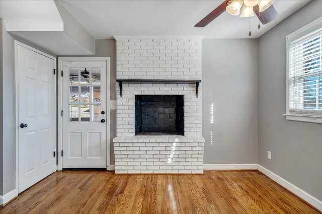 a view of an empty room with chandelier fan and wooden floor