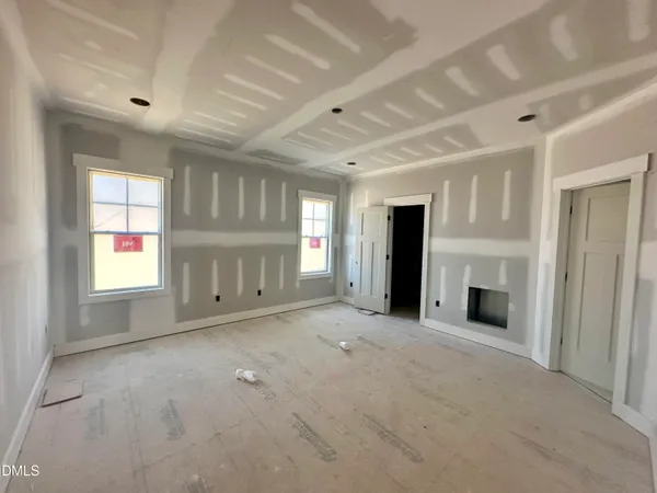 an empty room with windows and fireplace