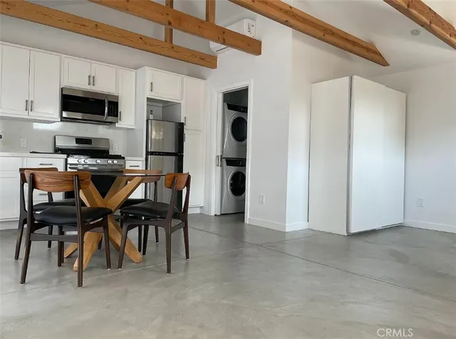 a dining room with stainless steel appliances granite countertop furniture and a kitchen view