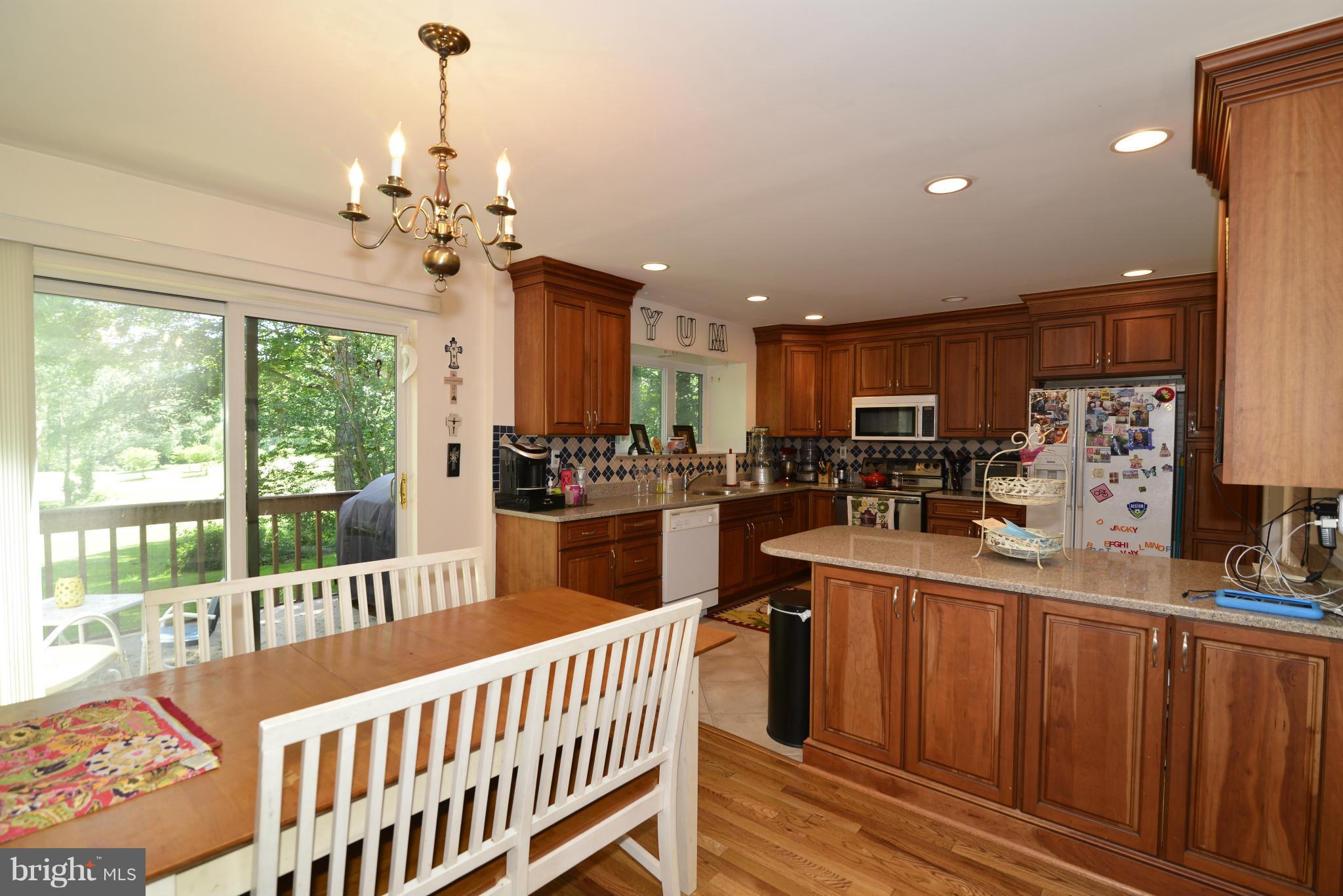 2065 Golf Course Drive Reston, VA 20191 - Photo 4 of 30 a kitchen with stainless steel appliances kitchen island granite countertop a refrigerator a sink dishwasher a stove and a dining table with wooden floor