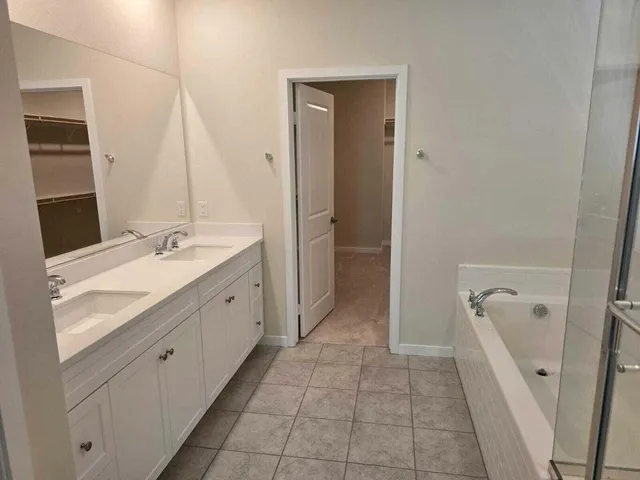 a spacious bathroom with a granite countertop sink a mirror and a bathtub