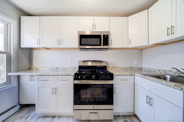 a kitchen with granite countertop white cabinets and stainless steel appliances