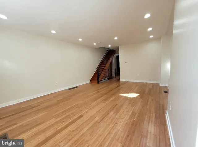 a view of an empty room with wooden floor and stairs