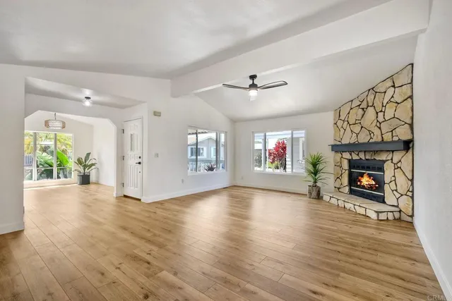 a view of an empty room with wooden floor fireplace and a window