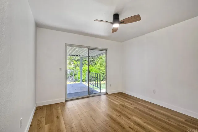 an empty room with wooden floor fan and windows