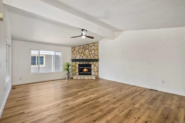 a view of an empty room with window and wooden floor