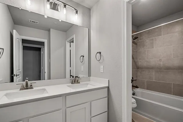 a bathroom with a double vanity sink mirror and a bathtub