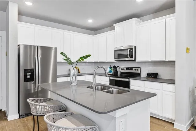 a kitchen with stainless steel appliances granite countertop a stove a refrigerator a sink a stove a dining table and chairs