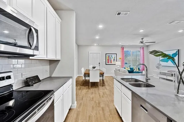 a kitchen with white cabinets a sink and wooden floor