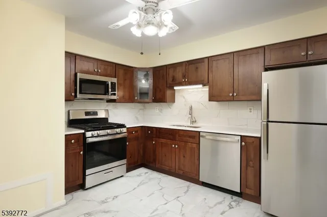 a kitchen with stainless steel appliances granite countertop a refrigerator stove a sink a microwave oven with cabinets and wooden floor