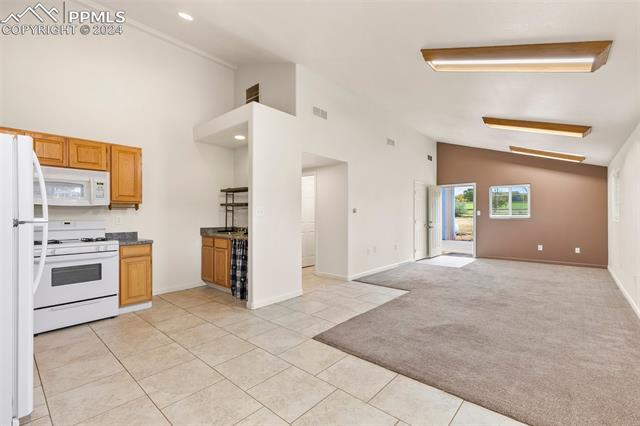 8740 Ermel Road Fountain, CO 80817 - Photo 3 of 3 Kitchen with light carpet, high vaulted ceiling, and white appliances