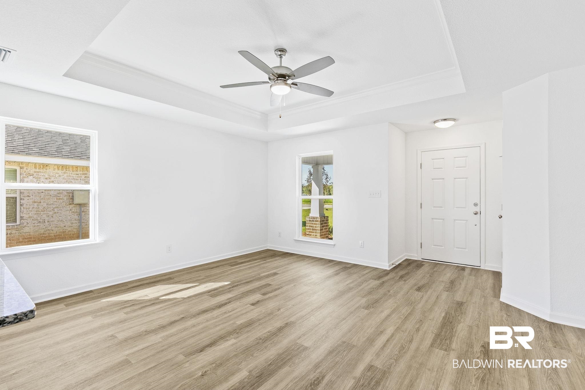 16014 Alabama Avenue Silverhill, AL 36576 - Photo 12 of 50 Unfurnished room featuring ceiling fan, a raised ceiling, and light hardwood / wood-style flooring