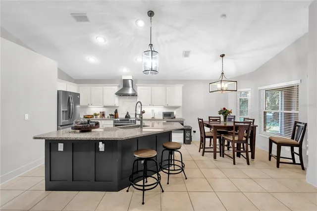 a view of a dining room and livingroom with furniture wooden floor a rug a painting and a chandelier