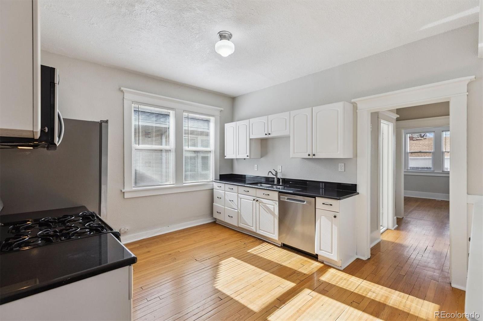 1411-1419 Meade Street Denver, CO 80204 - Photo 6 of 20 a kitchen with a stove a sink and a refrigerator