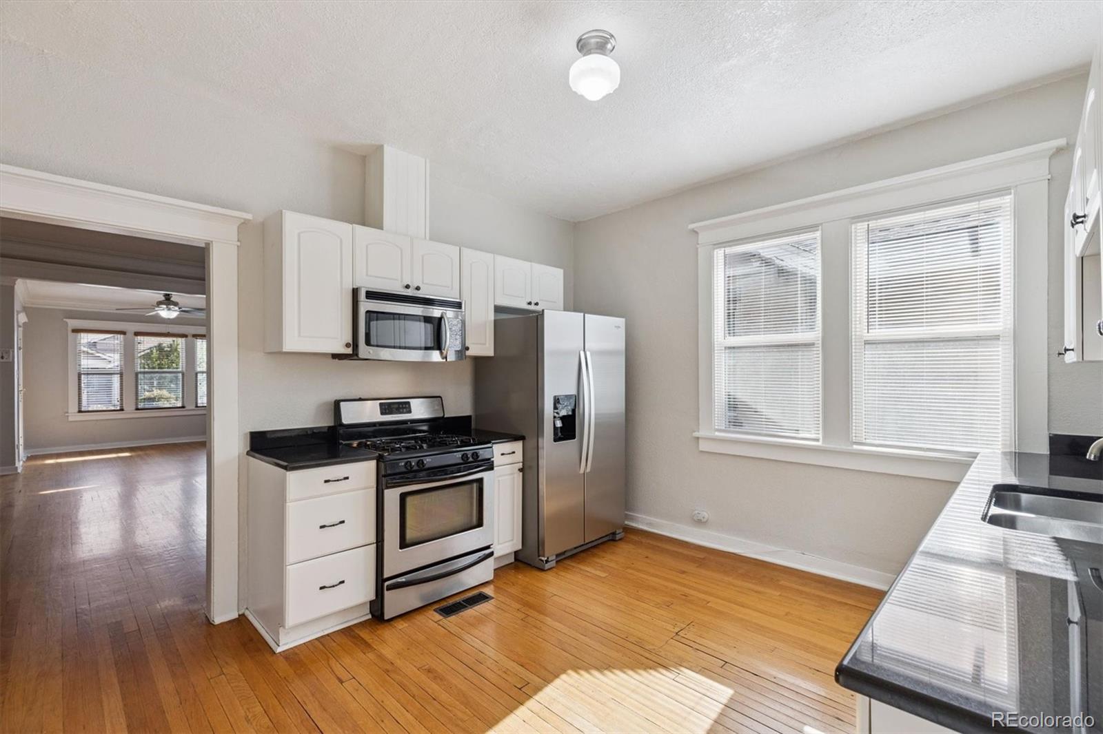 1411-1419 Meade Street Denver, CO 80204 - Photo 7 of 20 a kitchen with stainless steel appliances granite countertop a stove and a refrigerator