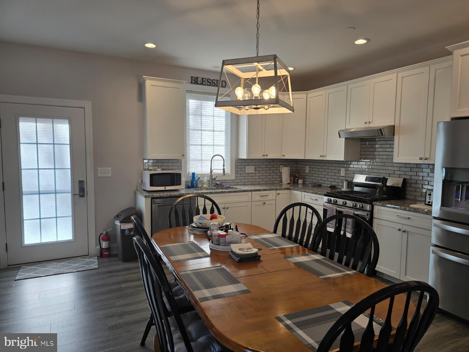 209 3rd Street Crumpton, MD 21628 - Photo 16 of 53 a kitchen with stainless steel appliances granite countertop a dining table chairs stove and white cabinets