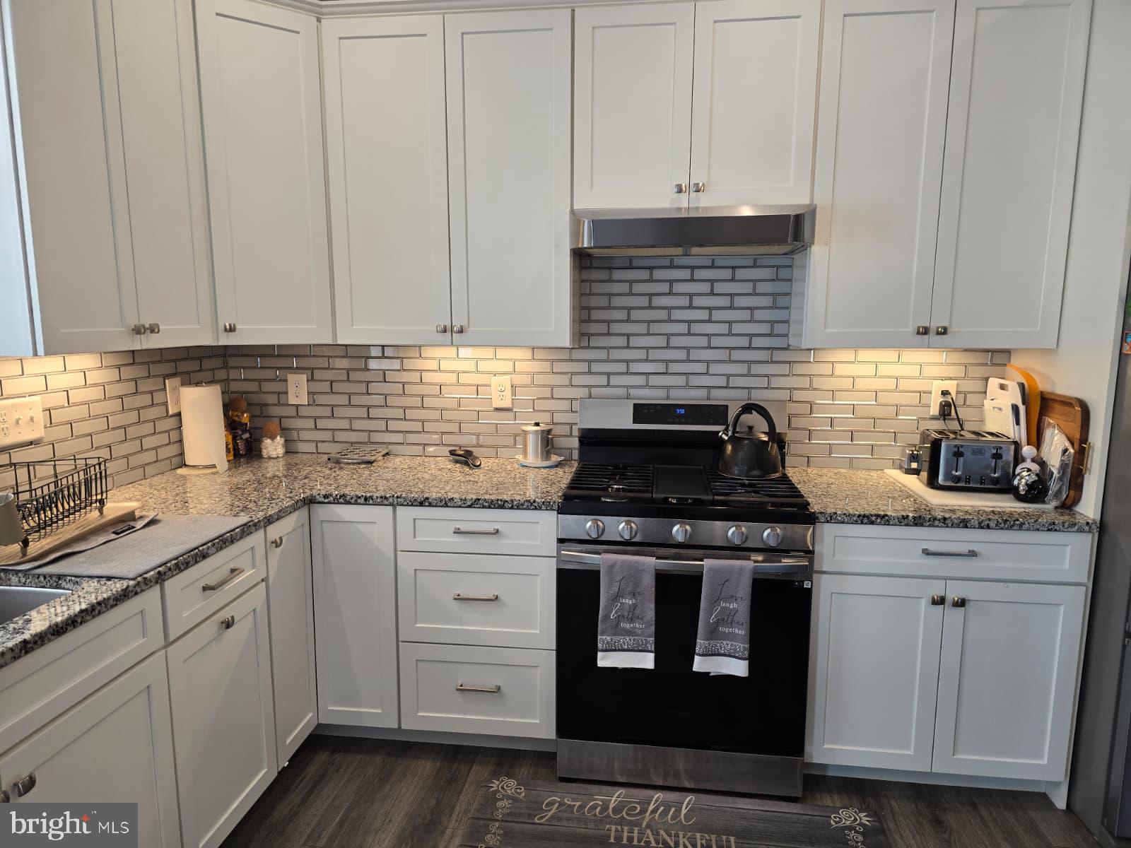 209 3rd Street Crumpton, MD 21628 - Photo 20 of 53 a kitchen with granite countertop white cabinets and stainless steel appliances