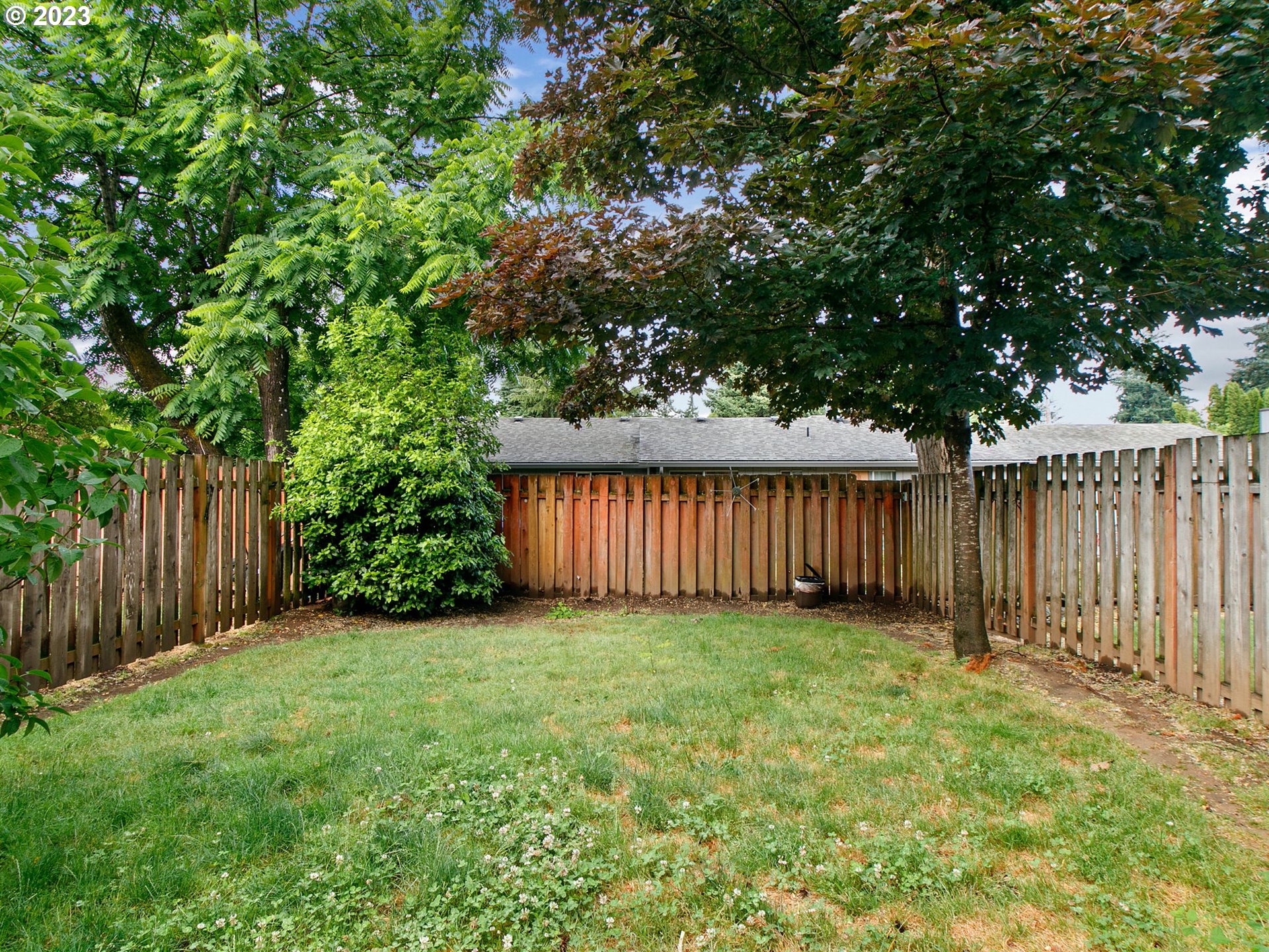 2369 Southeast 112th Avenue, Unit 7 Portland, OR 97216 - Photo 30 of 32 a view of a backyard with large trees and wooden fence
