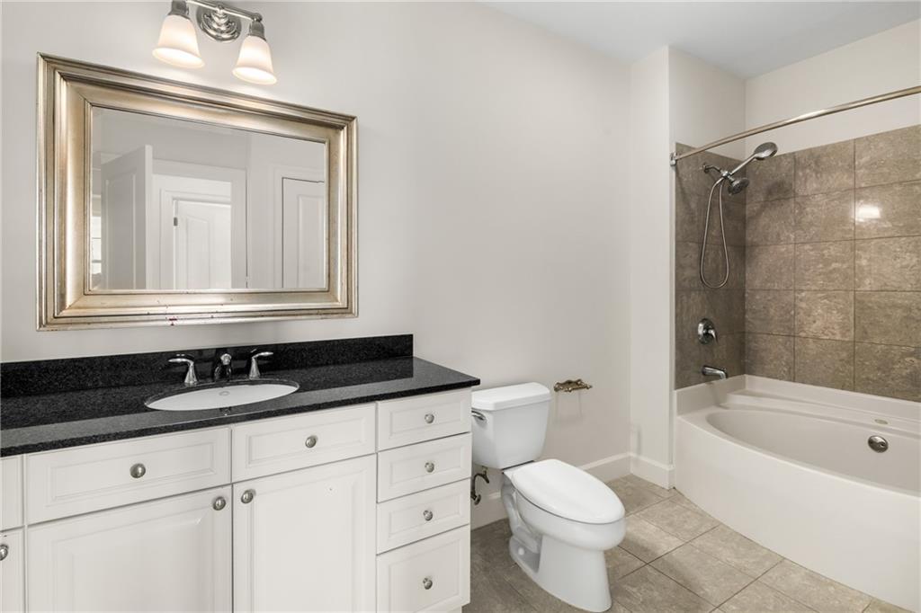 325 East Paces Ferry Road Northeast, Unit 1704 Atlanta, GA 30305 - Photo 28 of 29 a bathroom with a granite countertop sink a toilet a mirror and bathtub
