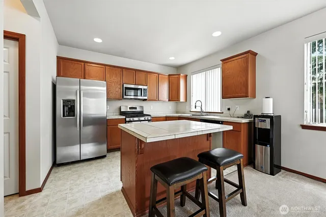 a kitchen with stainless steel appliances granite countertop a stove top oven a sink dishwasher a dining table and chairs with wooden floor