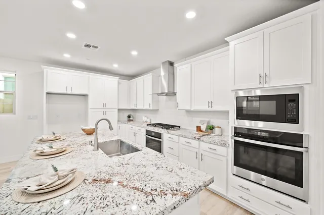 a kitchen with granite countertop white cabinets and a stove