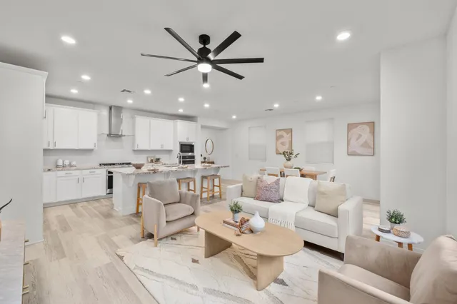a living room with furniture a flat screen tv and kitchen view