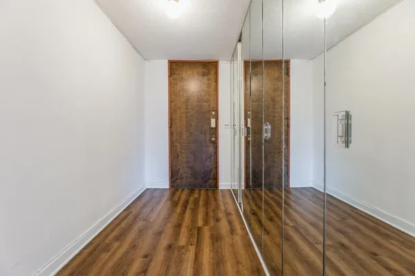 a view of a hallway with wooden floor and a bathroom
