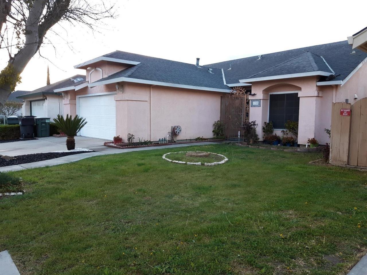 1205 Cribari Drive Modesto, CA 95358 - Photo 2 of 9 view of property exterior with a lawn, roof with shingles, stucco siding, and driveway