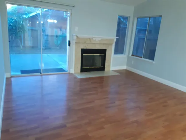 a view of a livingroom with wooden floor a fireplace and window