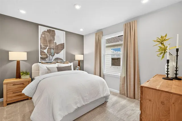 a bedroom with a bed and a potted plant on the dresser