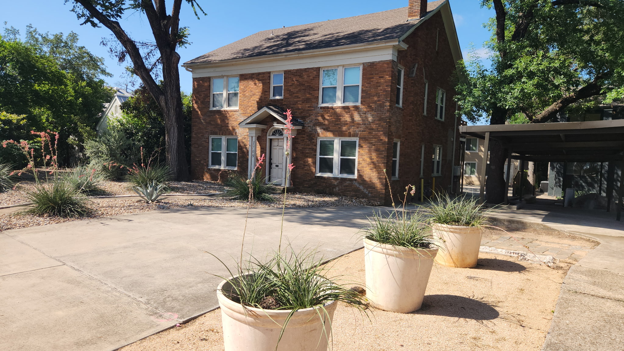 1709 Enfield Road, Unit A Austin, TX 78703 - Photo 7 of 8 A classic brick exterior with a welcoming entryway, complemented by mature trees and natural landscaping.