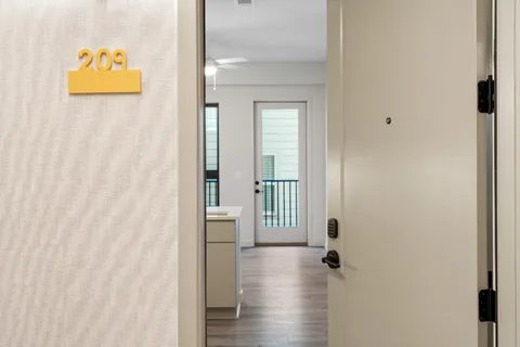 a view of a hallway with wooden floor and a bathroom