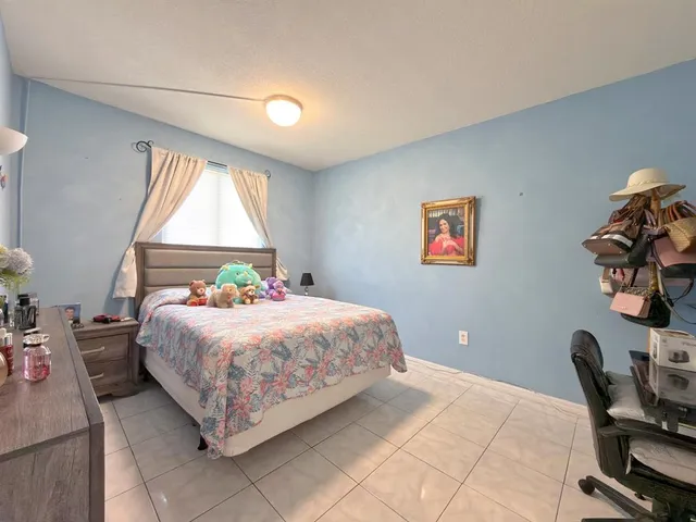 a bedroom with a bed a computer on the desk and a window