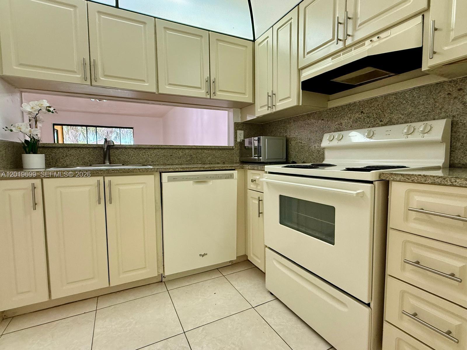 3470 Foxcroft Road, Unit 204 Miramar, FL 33025 - Photo 12 of 40 a kitchen with granite countertop white cabinets and white appliances