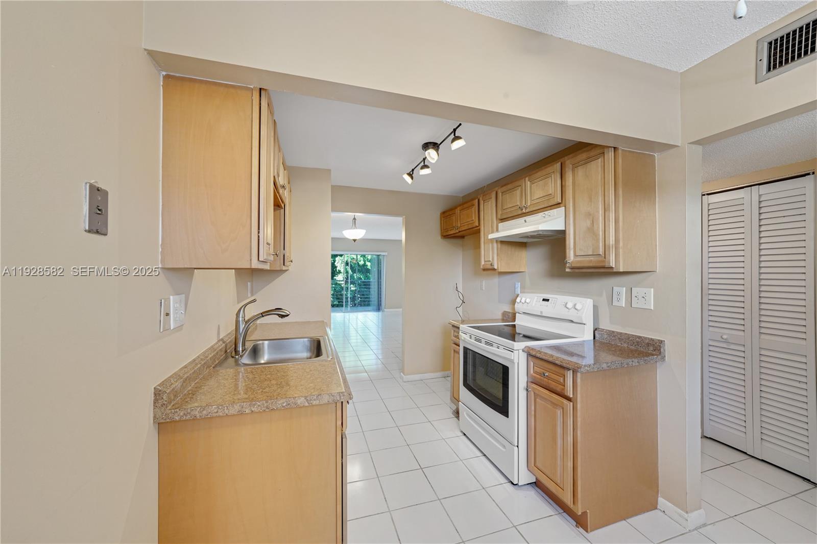 8305 Northwest 61st Street, Unit C305 Tamarac, FL 33321 - Photo 7 of 24 a kitchen with a stove sink and cabinets