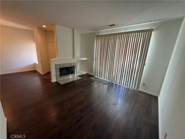 an empty room with wooden floor fireplace and windows