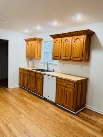 a kitchen with stainless steel appliances granite countertop a sink cabinets and wooden floor