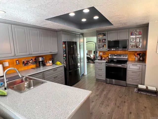 a kitchen with stainless steel appliances granite countertop a refrigerator a stove and a sink with wooden floor