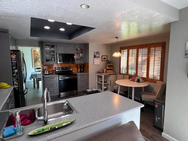 a room with stainless steel appliances kitchen island granite countertop a refrigerator a stove and a sink with wooden floor