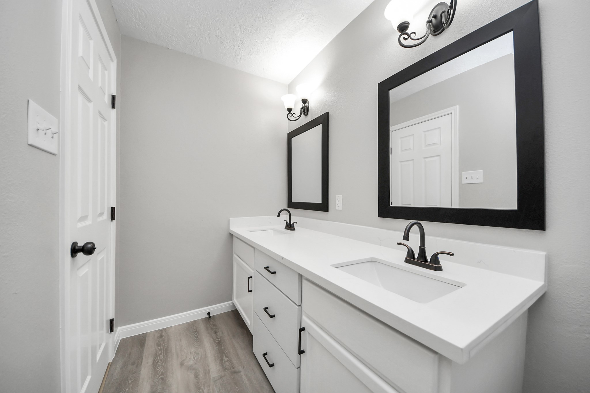 1105 East Kyle Road Clute, TX 77531 - Photo 33 of 44 The centrally located full bathroom features a sleek, modern design with dual sinks, elegant black fixtures, and large framed mirrors.