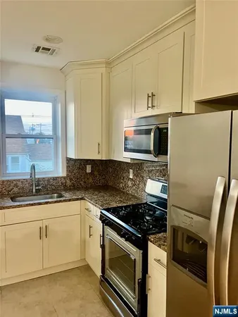 a kitchen with granite countertop a sink stove and refrigerator