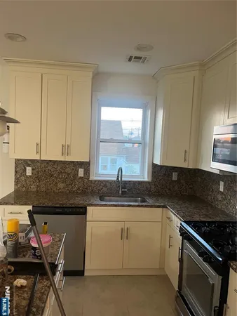 a kitchen with granite countertop a sink stove and cabinets